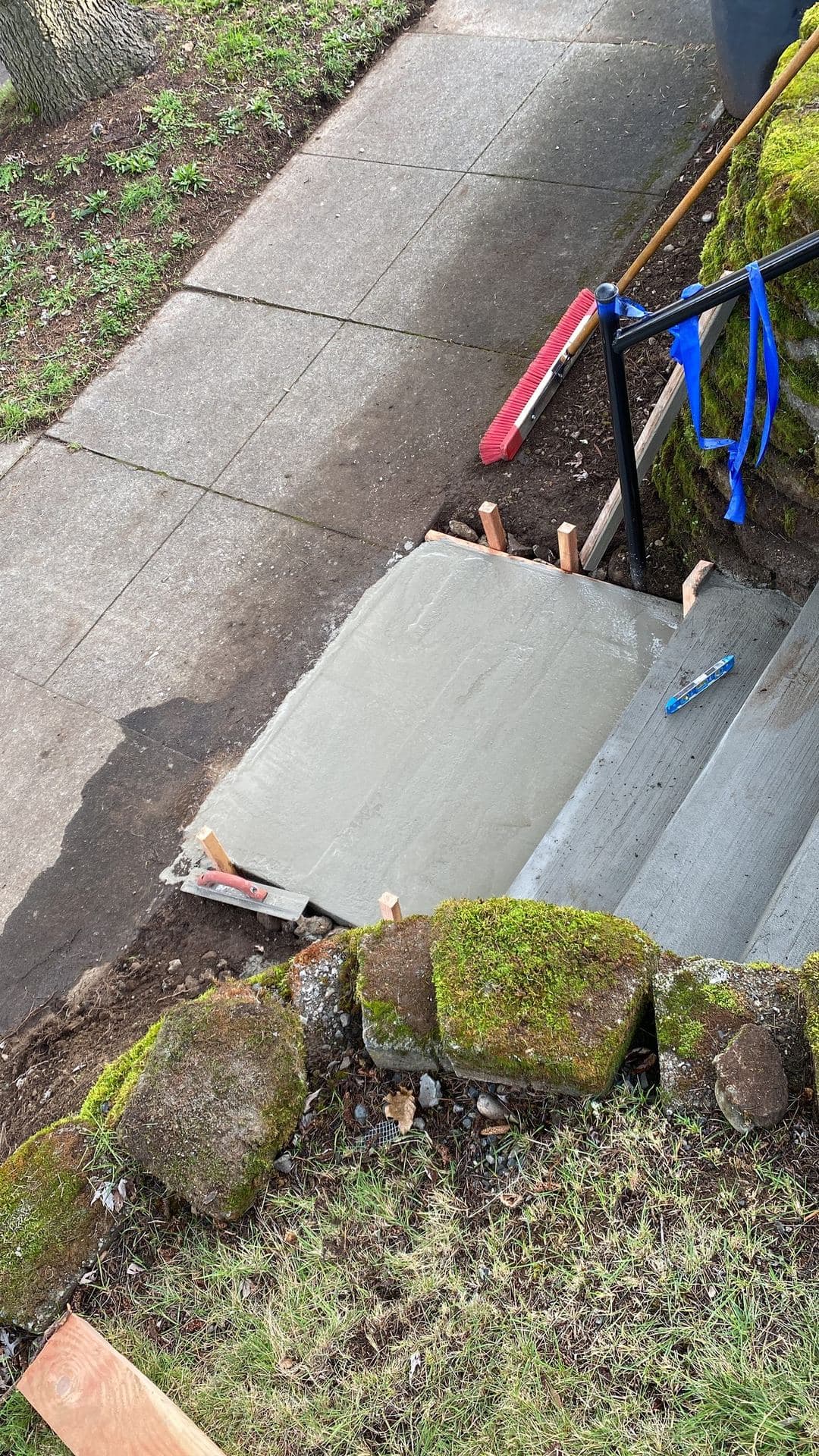 Fresh concrete landing pour in wood forms next to a sidewalk