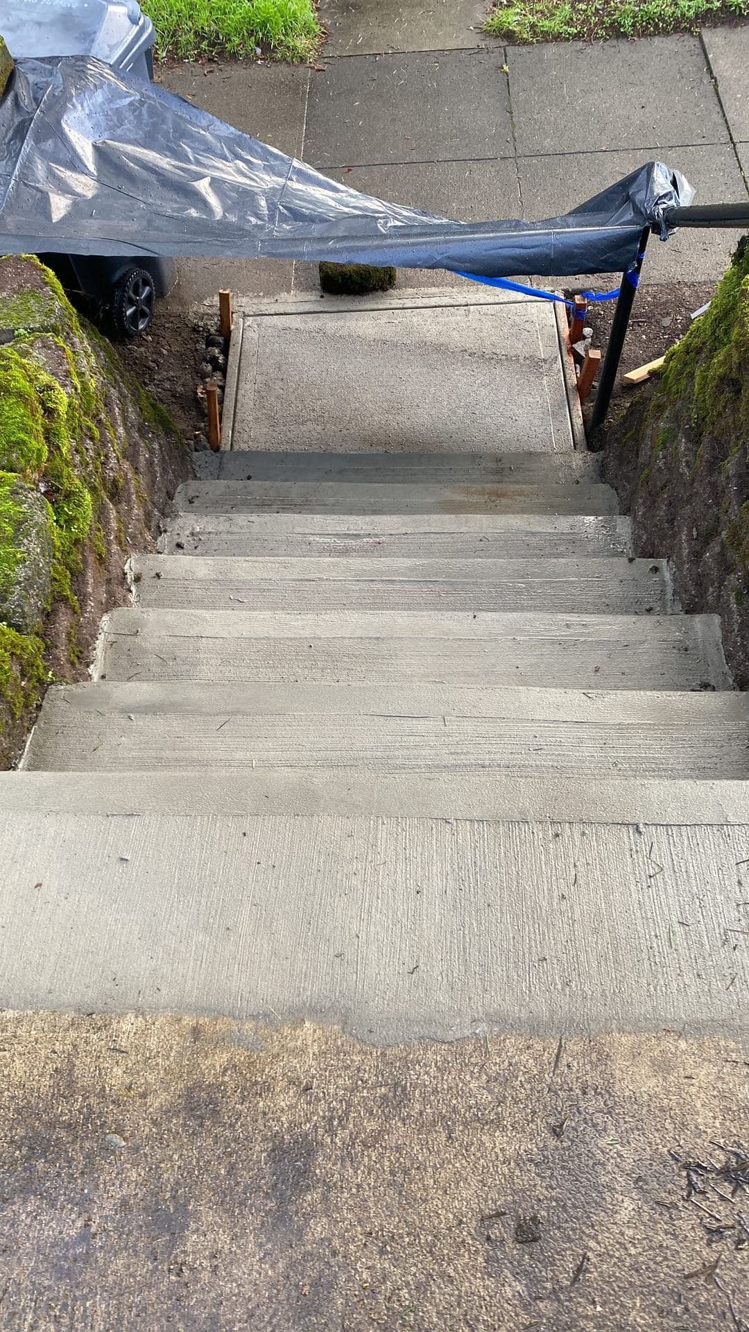 New broom-finished concrete steps and landing between mossy rock walls