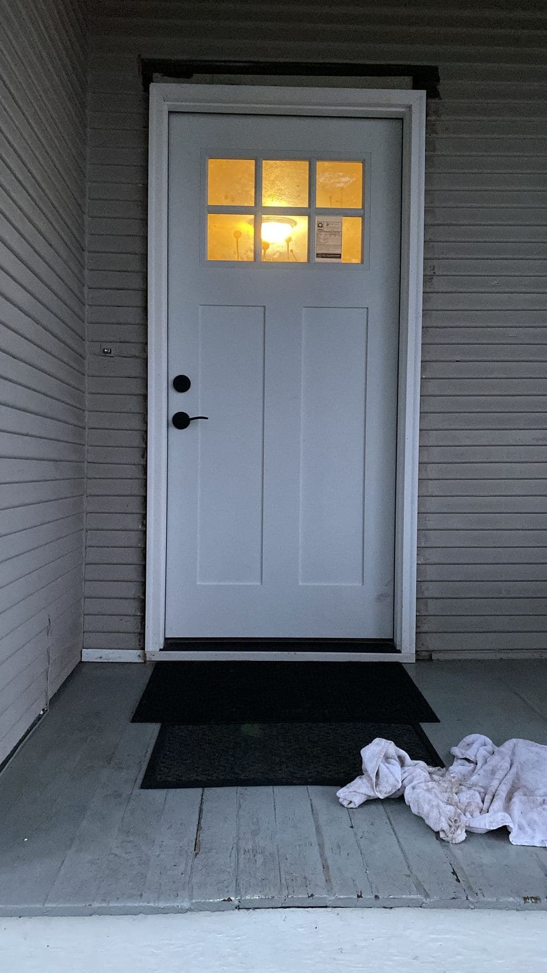 Primed entry door just set in its opening, shims and tools on the floor